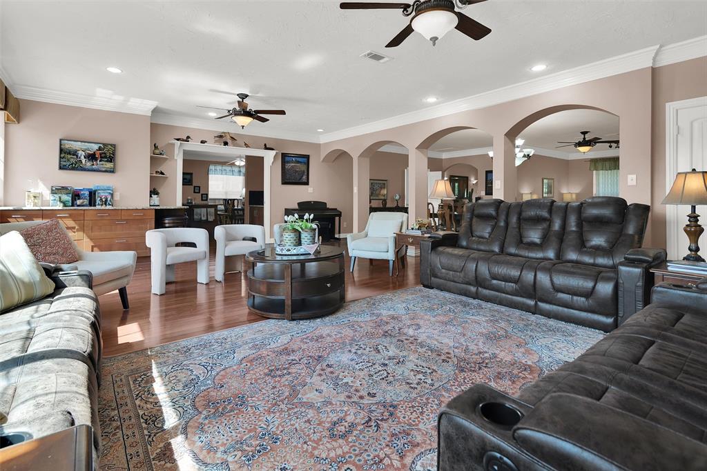 Hardwood-finish flooring, recessed lighting, crown molding, arched doorways, and built-in cabinetry