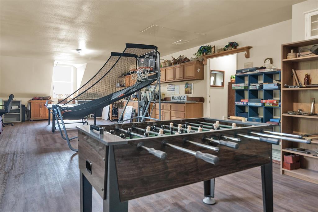 Wood-finish flooring throughout a spacious room, featuring a built-in wooden shelving unit, a built-in blue storage unit, and wood-finish cabinetry