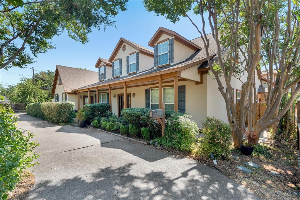 Two-story residence featuring dormer windows, a covered front porch with supporting columns, and a driveway Two-story residence featuring dormer windows, a covered front porch with supporting columns, and a driveway