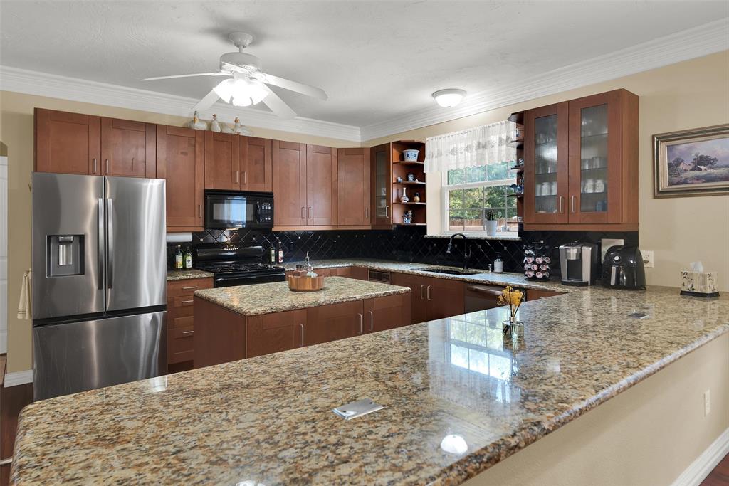 Kitchen featuring wood cabinetry, stainless steel appliances, a center island, and granite countertops