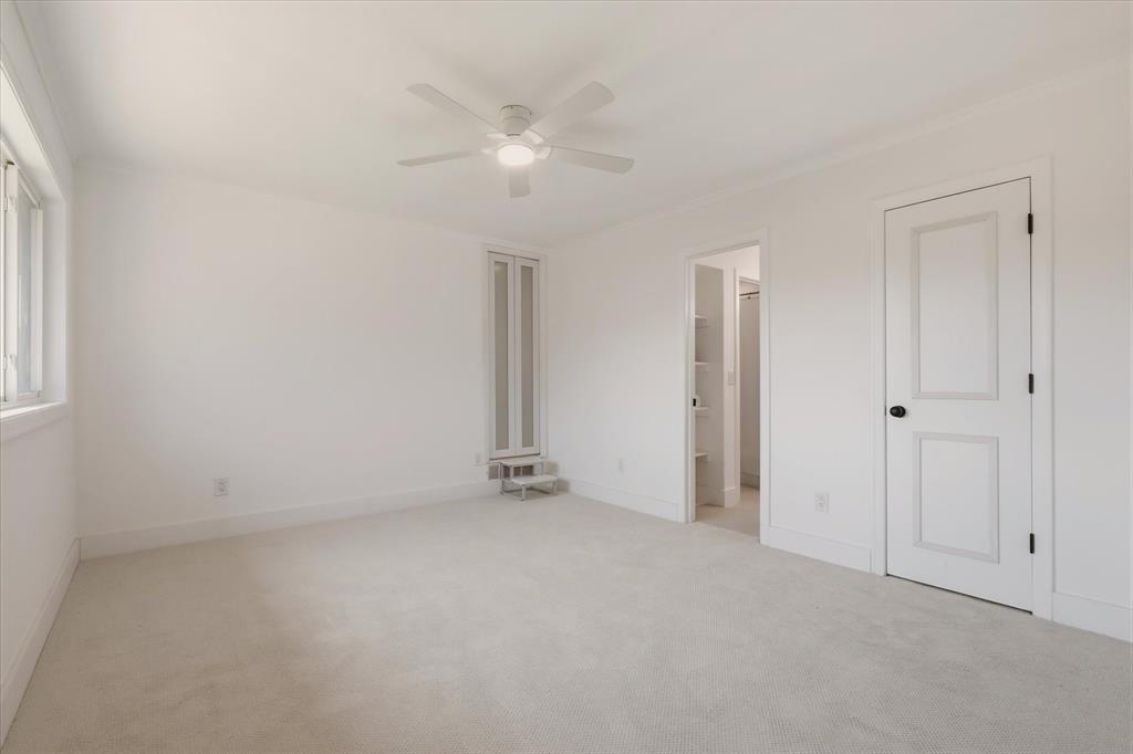 Wall-to-wall carpeting, white painted walls, a built-in ceiling fan with integrated lighting, and multiple paneled doors