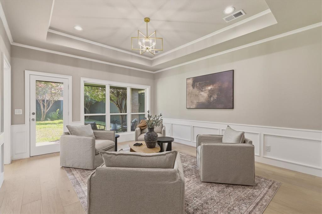 Tray ceiling with an ornamental chandelier, recessed lighting, wood-finish flooring, wainscoting, and large windows