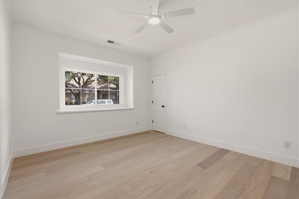 Recessed window with white trim, light wood-finish flooring, white walls, ceiling fan with integrated lighting, and crown molding