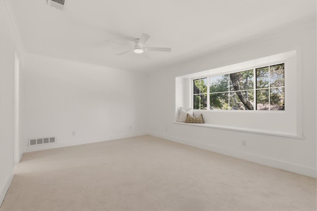 Expansive room with neutral carpet, large picture window, and a built-in window seat