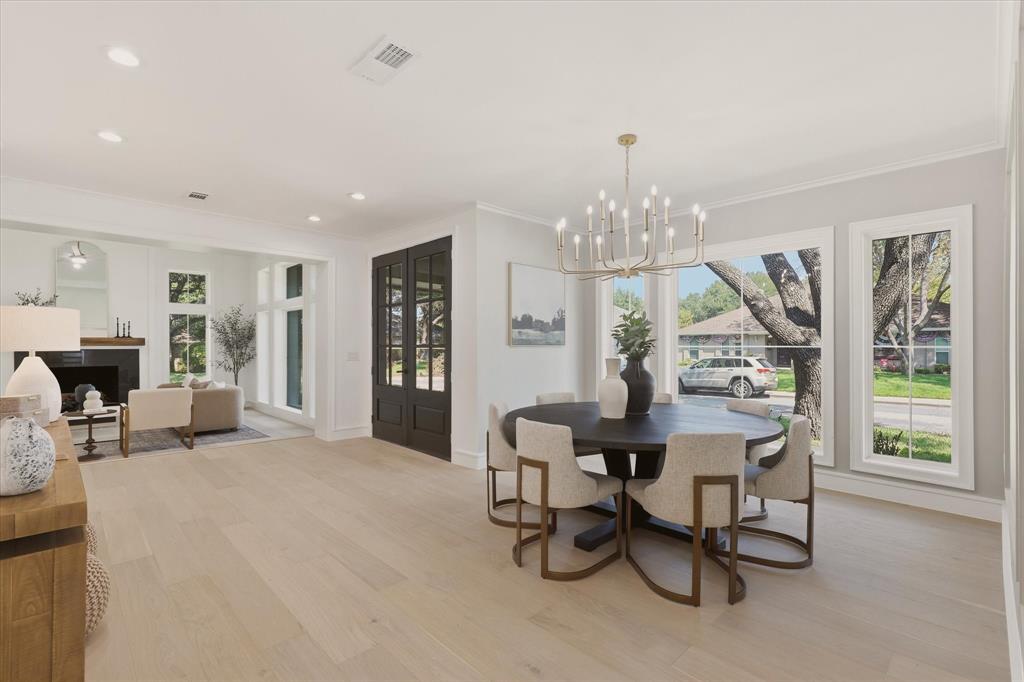 Expansive room featuring wood-finish flooring, recessed lighting, a fireplace with a dark mantel, multiple large windows, and a chandelier