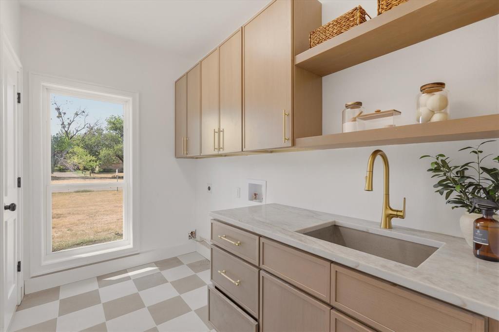 White checkered flooring, built-in cabinetry, floating shelves, undermount sink, and brass-finish faucet