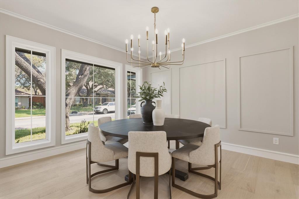 Spacious room featuring multiple large windows, a distinctive chandelier, and light wood-finish flooring