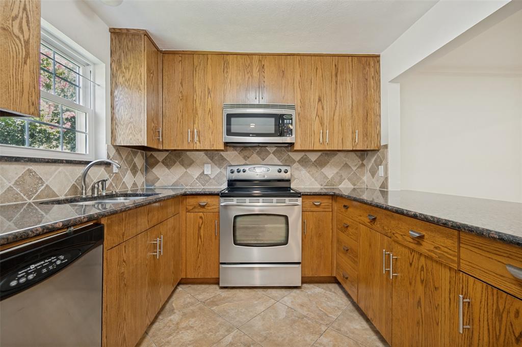 U-shaped kitchen featuring wood-finish cabinetry, stainless steel appliances, and a tiled backsplash