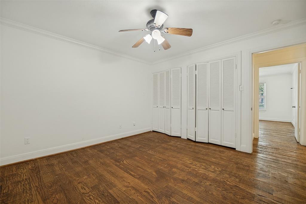 Hardwood flooring, crown molding, white louvered bifold doors, and a ceiling fan with integrated lighting