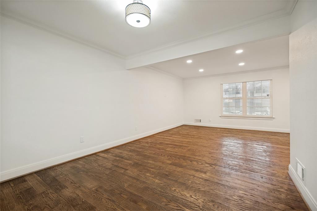 Wood-finish flooring, white walls, recessed lighting, and a drum pendant light fixture