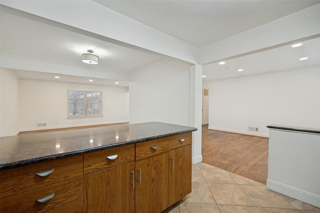 Kitchen island with wood cabinetry, dark countertop, and brushed nickel hardware