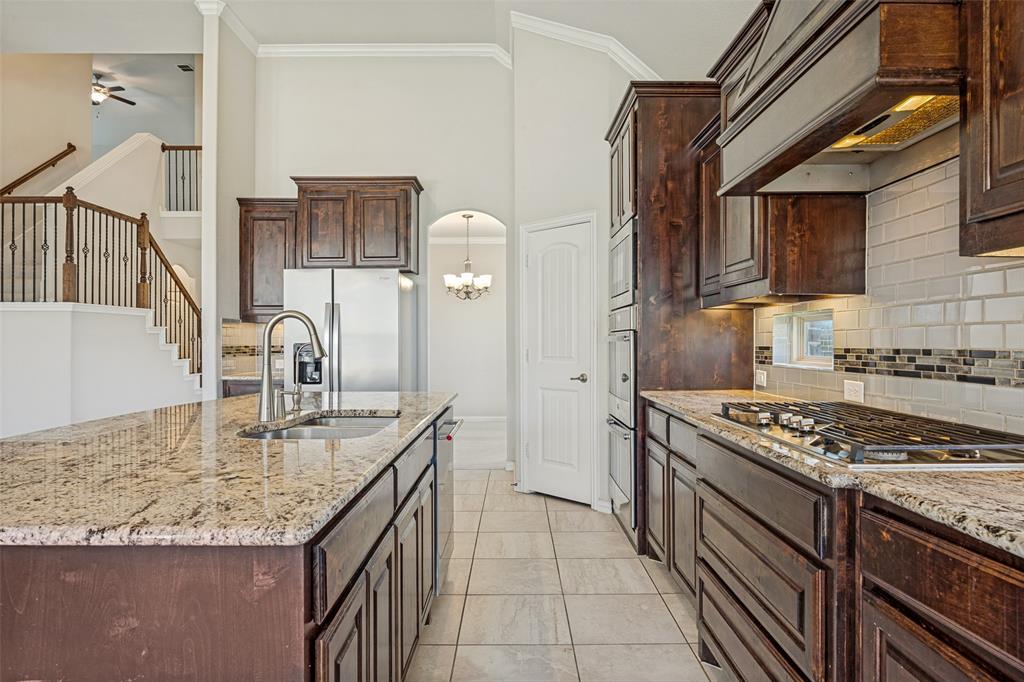 Kitchen featuring granite countertops, wood cabinetry, stainless steel appliances, and a gas cooktop