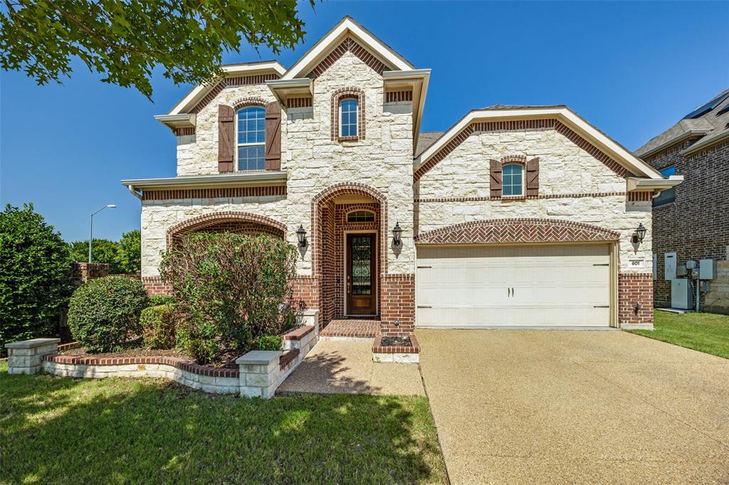Stone and brick exterior with arched entryways, a two-car garage, and established landscaping