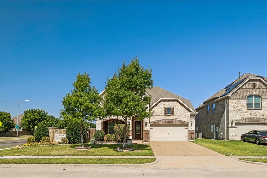 Stone and brick facade, arched entryway, attached two-car garage, established front landscaping, and concrete driveway