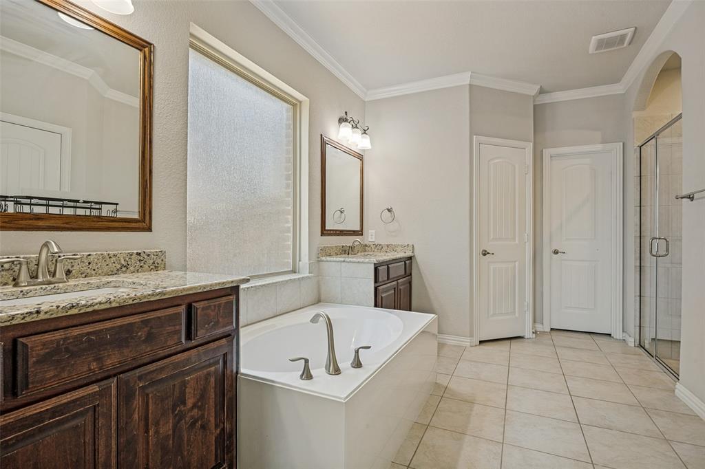 Dual vanity with granite countertops, a built-in soaking tub, a separate glass-enclosed shower, and tile flooring