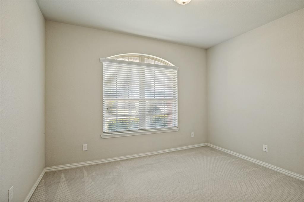 Arched window with blinds, light gray wall paint, and gray carpeting