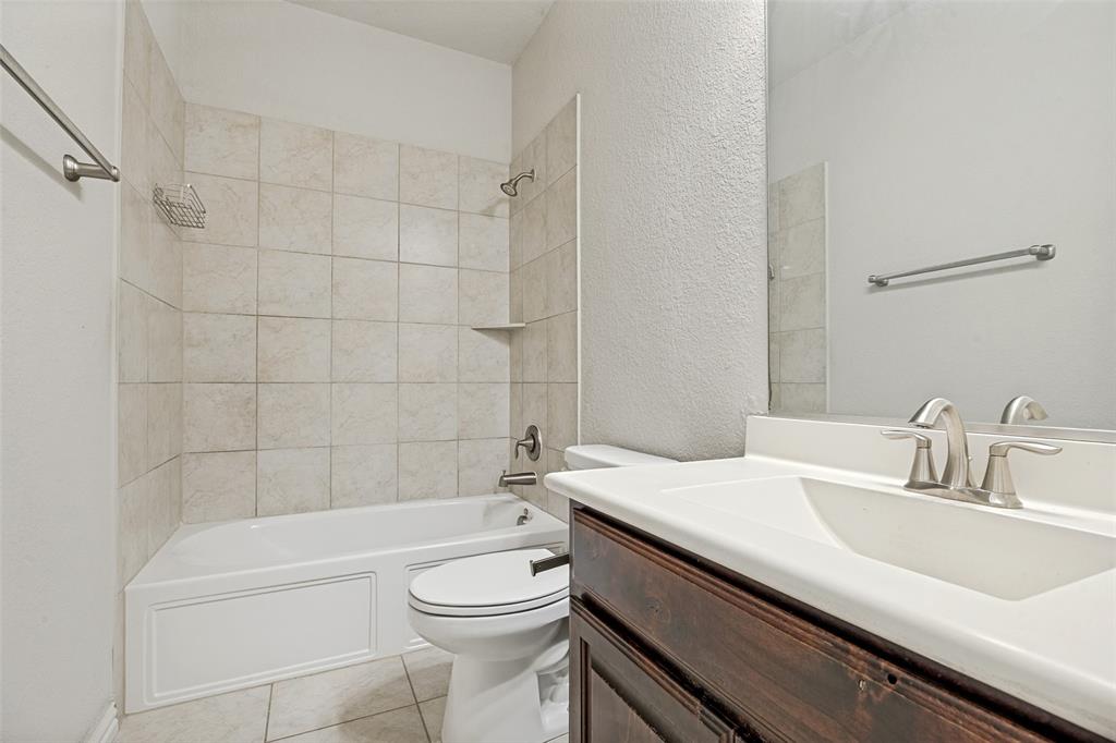 White bathtub with tile surround, a built-in shelf, and a shower fixture