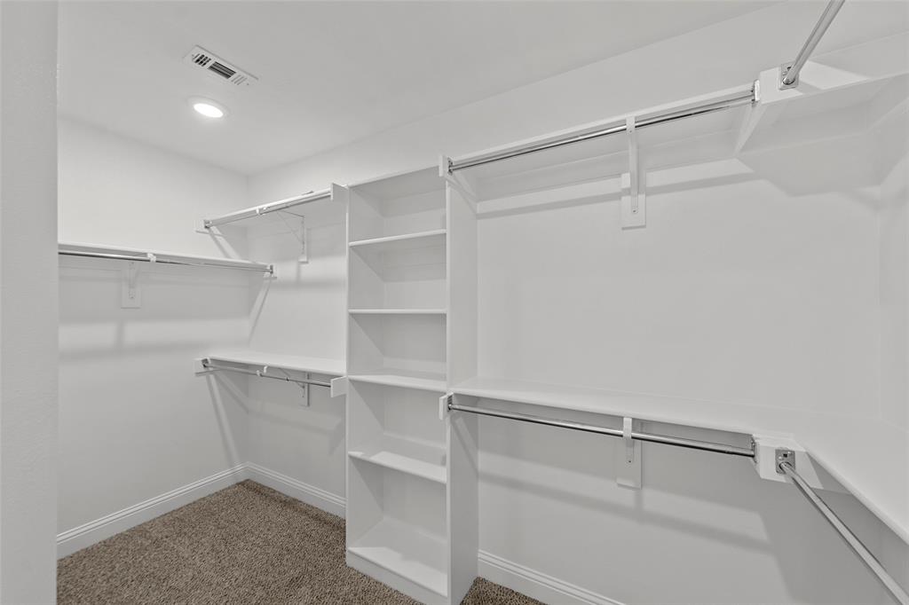 Walk-in closet with integrated shelving, multiple hanging rods, built-in vertical storage, recessed lighting, and carpeted flooring