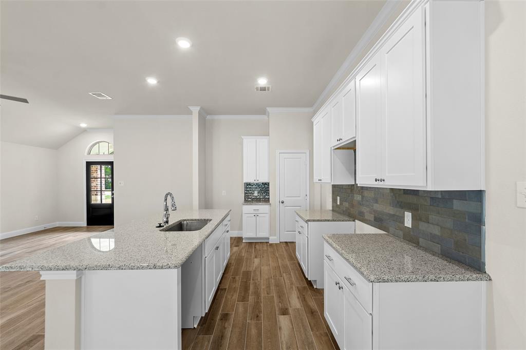 Kitchen featuring white cabinetry, light-toned countertops, subway tile backsplash, and wood-finish flooring