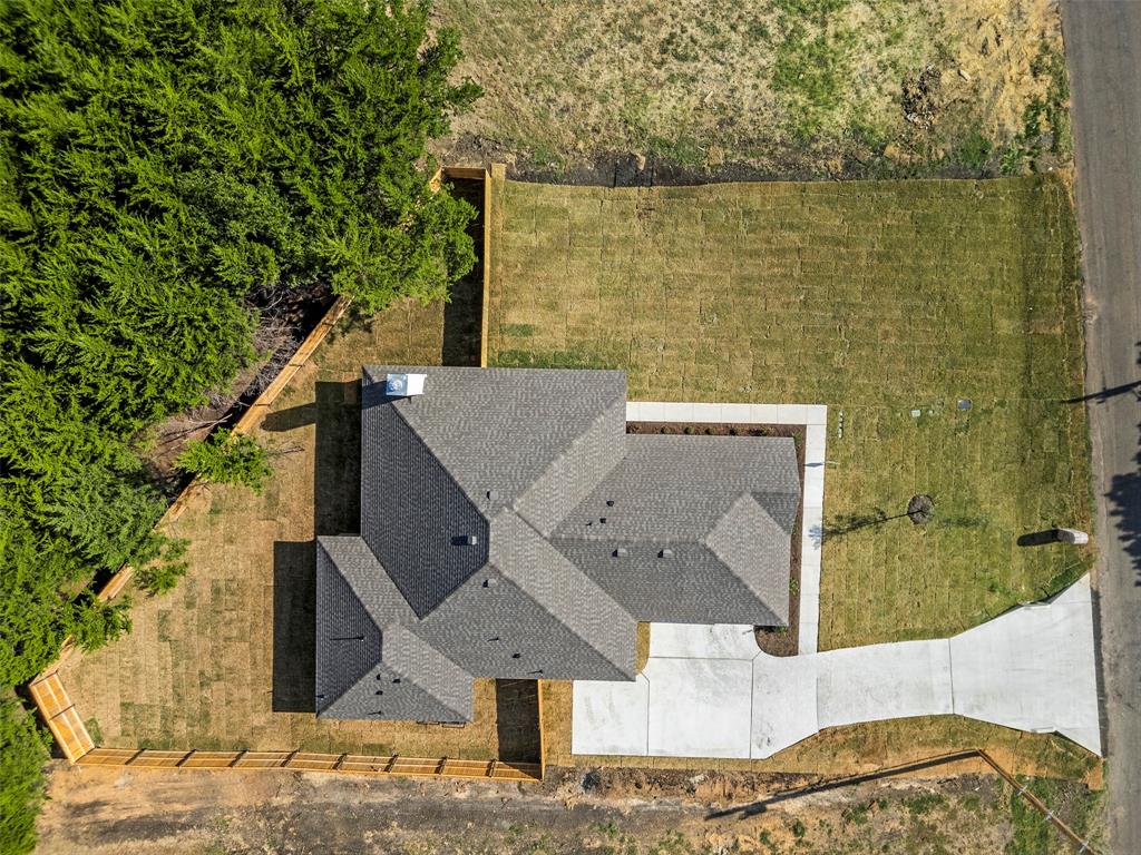 Gable roofline, concrete driveway, concrete sidewalk, fenced perimeter, and established landscaping