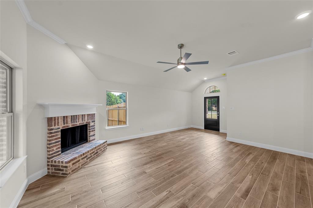 Vaulted ceiling with recessed lighting, brick-clad fireplace, wood-finish flooring, and ceiling fan