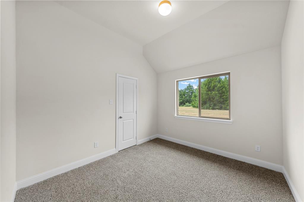 Vaulted ceiling, neutral wall paint, light-colored carpet, rectangular window, and a single ceiling-mounted light fixture