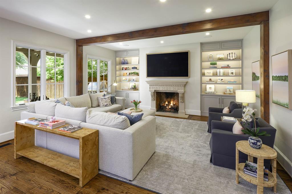 Living room with gas fireplace, wood beamed ceiling, and built-in cabinetry and custom built ins