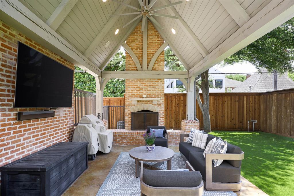 Outdoor covered loggia with wood beamed vaulted ceiling and gas fireplace