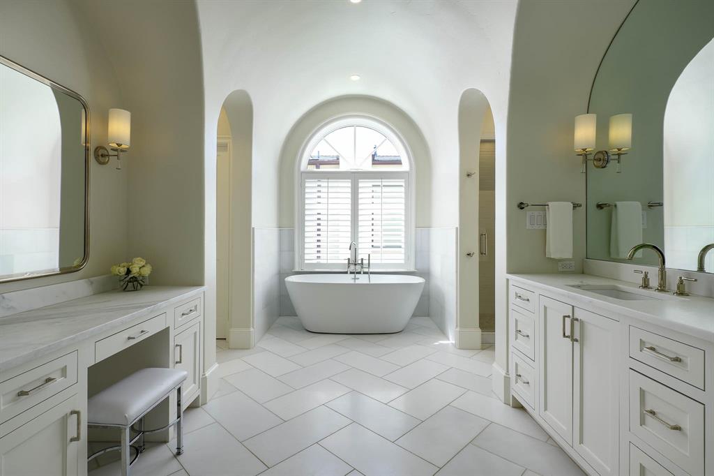 Primary bathroom with dual vanities, stand alone tub, and dual large walk-in closets
