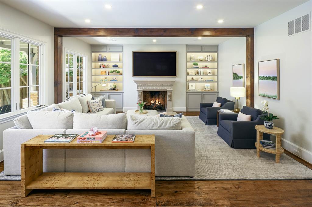 Living room with lgas fireplace, wood beamed ceiling, and built-in cabinetry and shelving
