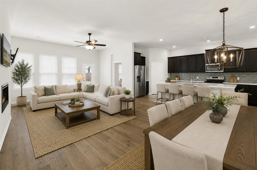 Looking back towards the heart of the home, this angle showcases the dining area’s placement within the grand great room, framed by the modern kitchen with its sophisticated dark cabinetry, sleek subway tile backsplash, and spacious island. The integrated ceiling fan and recessed lighting create a comfortable atmosphere for everyday family meals or celebrating special occasions with a smooth transition to after-dinner relaxation. *Virtually Staged* Looking back towards the heart of the home, this angle showcases the dining area’s placement within the grand great room, framed by the modern kitchen with its sophisticated dark cabinetry, sleek subway tile backsplash, and spacious island. The integrated ceiling fan and recessed lighting create a comfortable atmosphere for everyday family meals or celebrating special occasions with a smooth transition to after-dinner relaxation. *Virtually Staged*