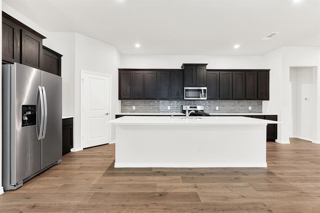 From this straight-on angle, the kitchen's wide, functional layout is clear, anchored by the oversized central island. It's the perfect central hub for casual morning breakfasts, setting out party appetizers, or just hanging out. From this straight-on angle, the kitchen's wide, functional layout is clear, anchored by the oversized central island. It's the perfect central hub for casual morning breakfasts, setting out party appetizers, or just hanging out.