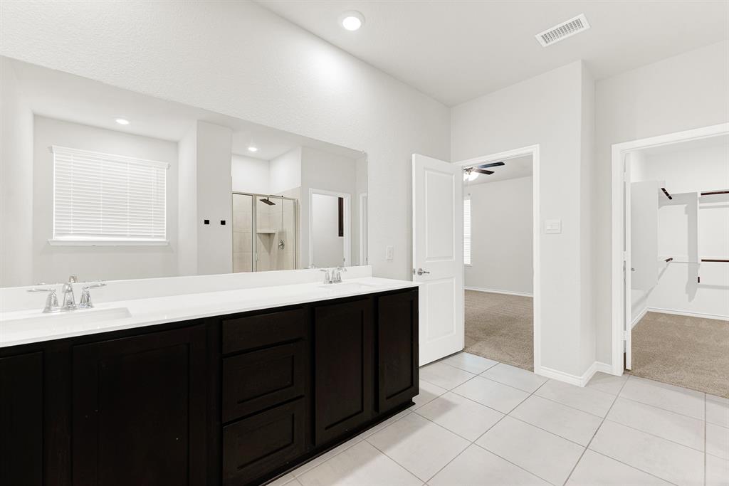 A critical viewpoint connecting all parts of the suite, this photo shows the spacious vanity, the clear flow to the main bedroom, and the entrance to the impressive walk-in closet. Effortless living defines this well-planned layout, perfectly connecting morning routines, wardrobe selection, and rest.