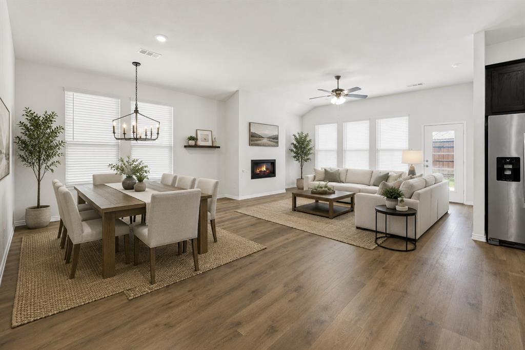A wide angle highlights the spacious open concept layout where extensive LVP wood-look flooring connects the dining area, featuring an inviting fireplace and ample natural light from multiple windows, to the adjacent kitchen. It is the perfect setup for effortless entertaining, allowing conversations to flow easily from dinner prep to relaxing by the fire with friends and family. *Virtually Staged* A wide angle highlights the spacious open concept layout where extensive LVP wood-look flooring connects the dining area, featuring an inviting fireplace and ample natural light from multiple windows, to the adjacent kitchen. It is the perfect setup for effortless entertaining, allowing conversations to flow easily from dinner prep to relaxing by the fire with friends and family. *Virtually Staged*