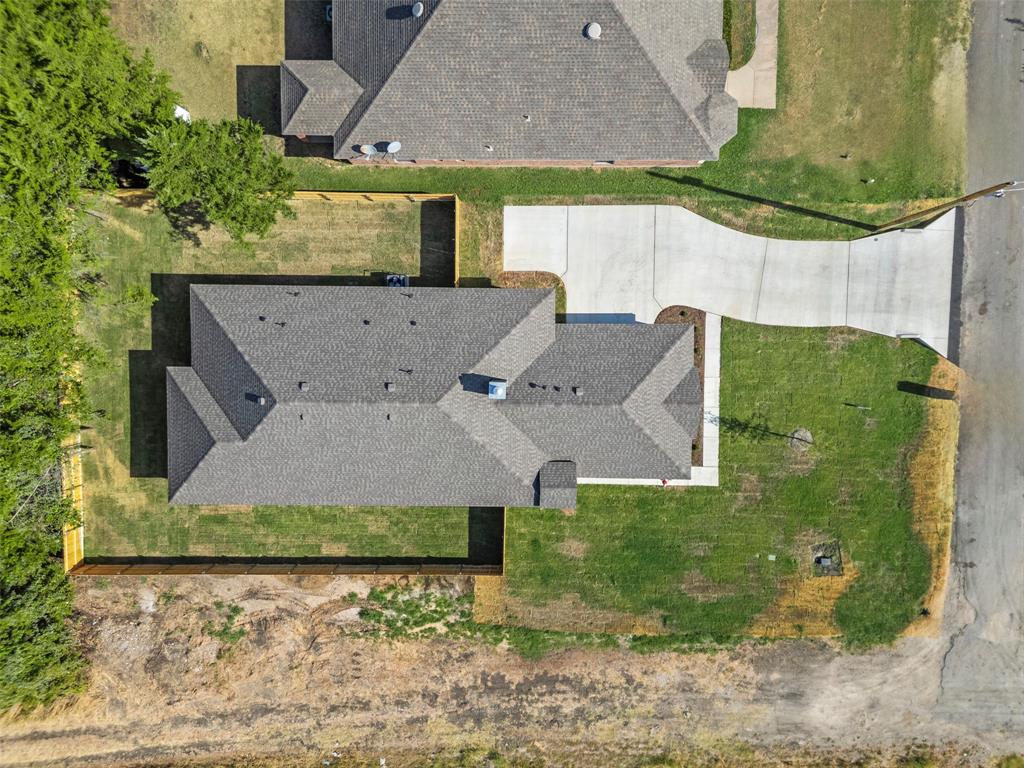 Residential property featuring a gray shingle roof, concrete driveway, and a partially fenced backyard
