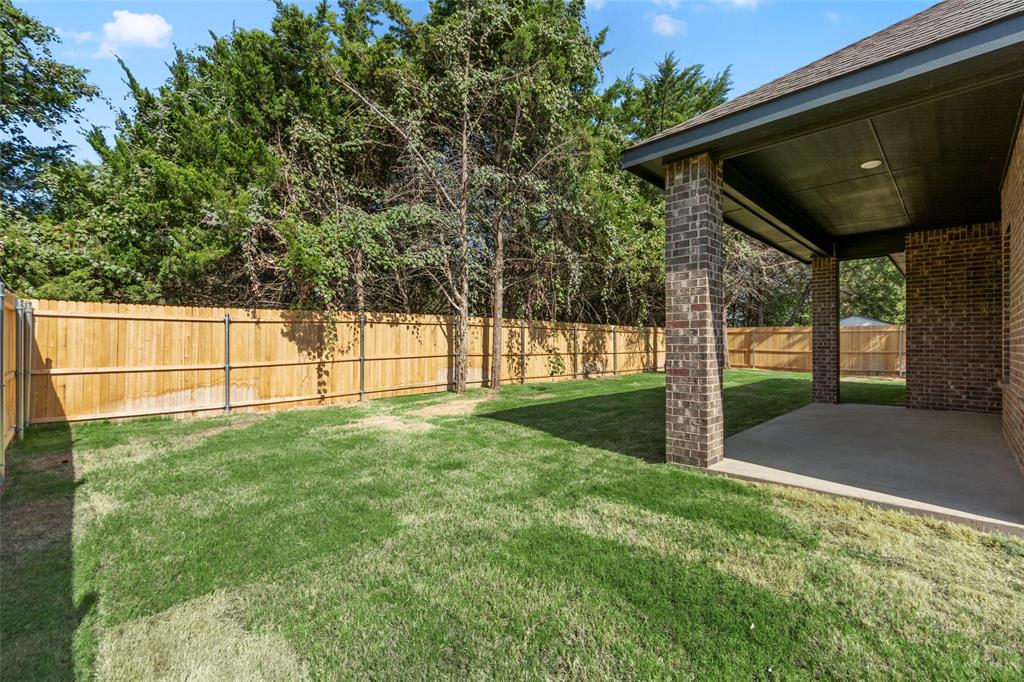 Expansive grassy yard with wood fencing and mature trees