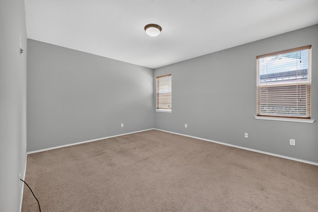 Neutral tone wall paint, carpeted flooring, two windows with blinds, and a flush-mount ceiling light