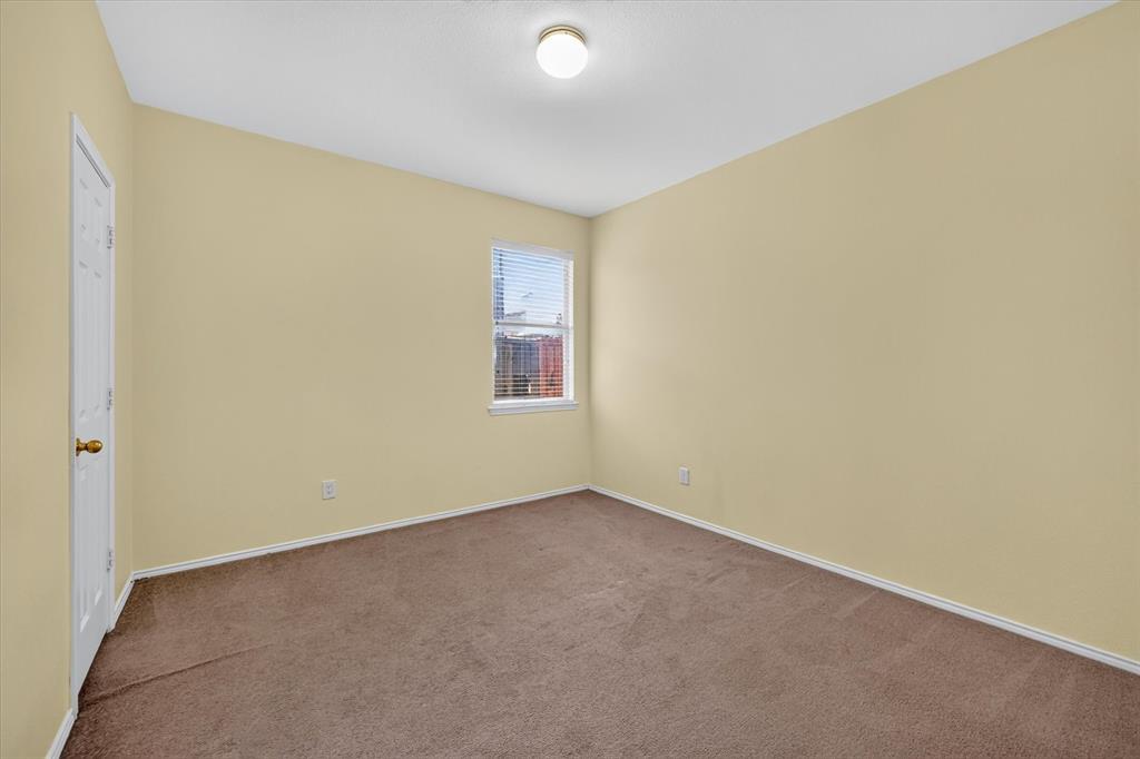 Neutral tone wall paint, carpeted flooring, two windows with blinds, and a flush-mount ceiling light