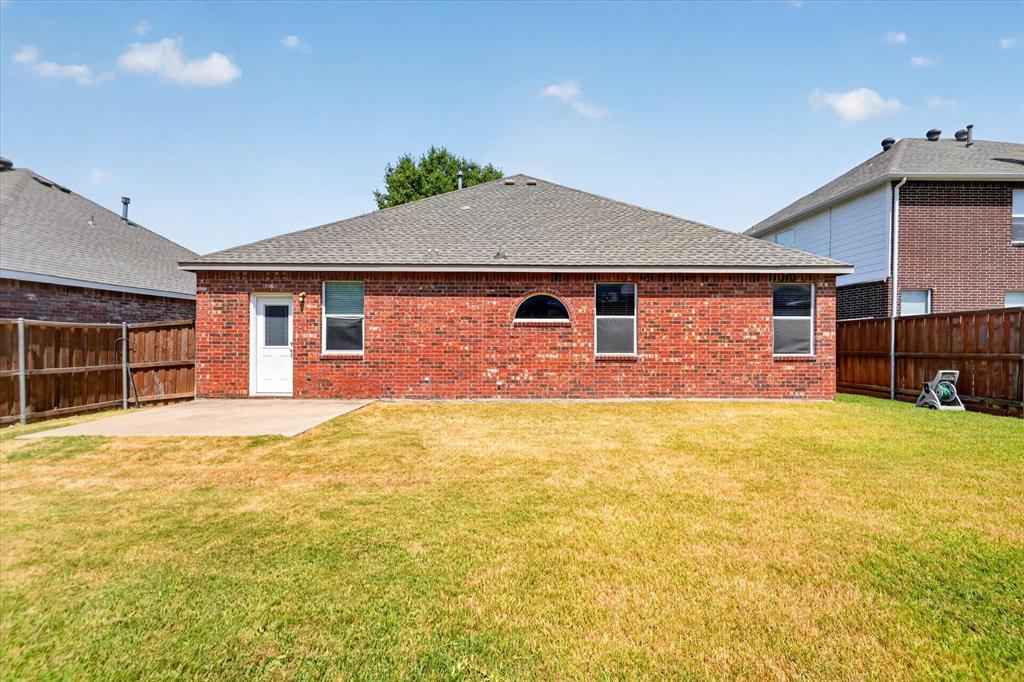 Expansive backyard with a large grass lawn, privacy fencing, and a concrete patio