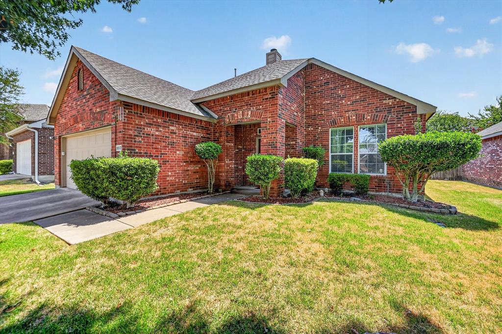Red brick exterior with a grey shingle roof, attached garage, and landscaping