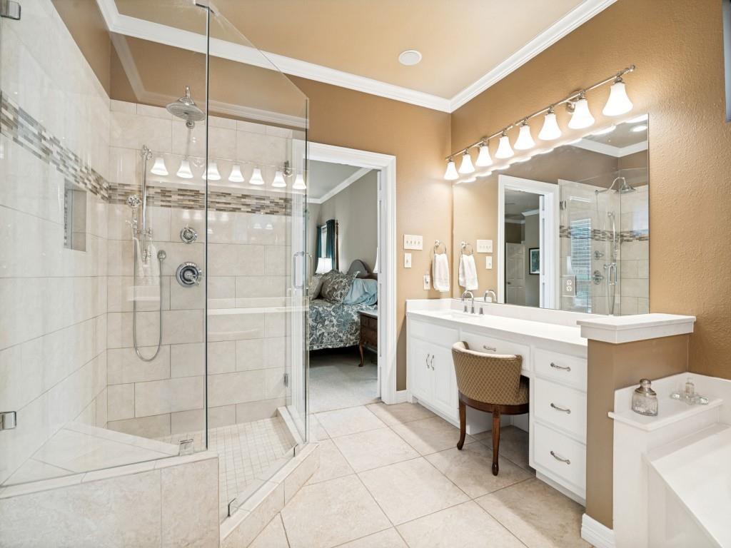 The ensuite primary bathroom features tiled shower with glass surround and separate vanities.