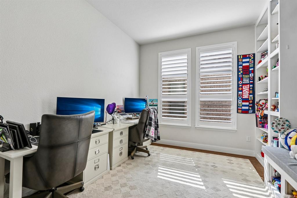 Recessed wall shelving, two windows with louvered shutters, and wood-finish flooring