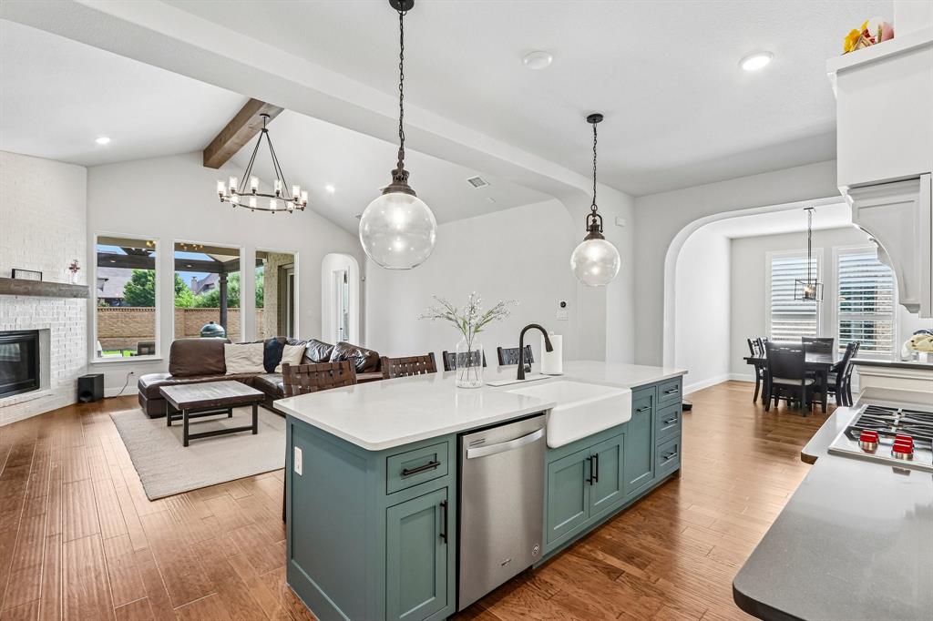 Kitchen island with an integrated farmhouse sink, stainless steel dishwasher, and pendant lighting Kitchen island with an integrated farmhouse sink, stainless steel dishwasher, and pendant lighting