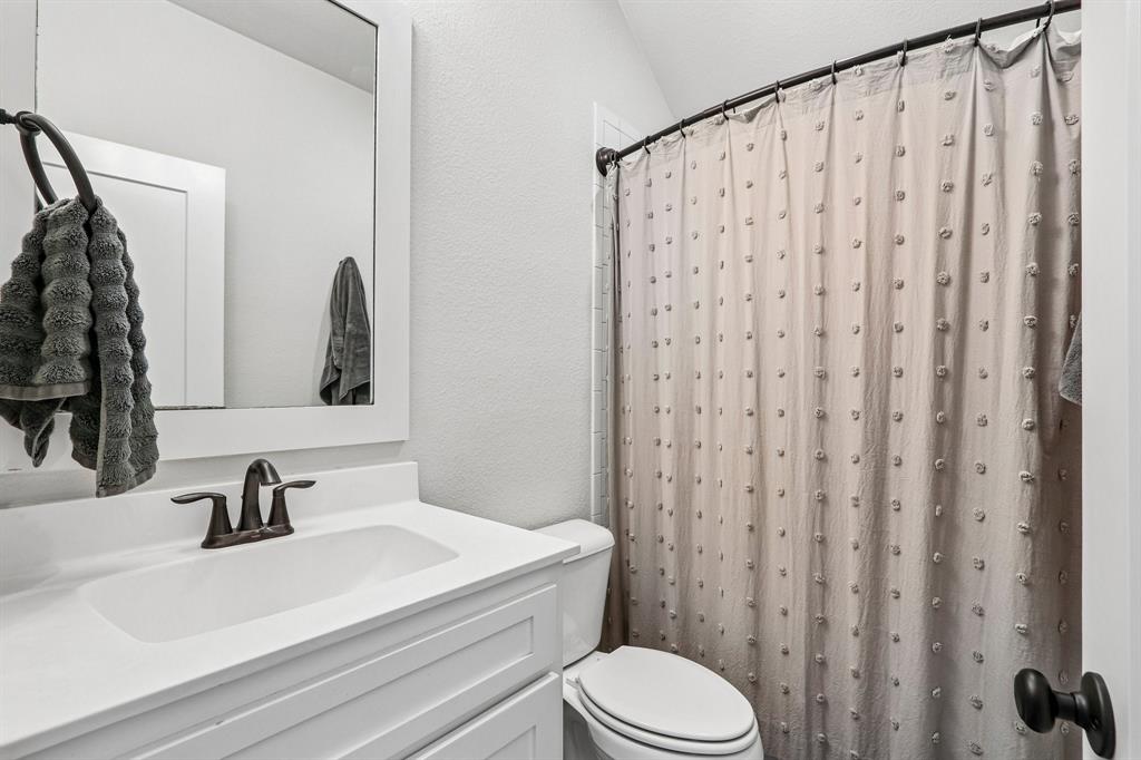 White vanity with integrated sink, bronze-finish faucet, and coordinating mirror