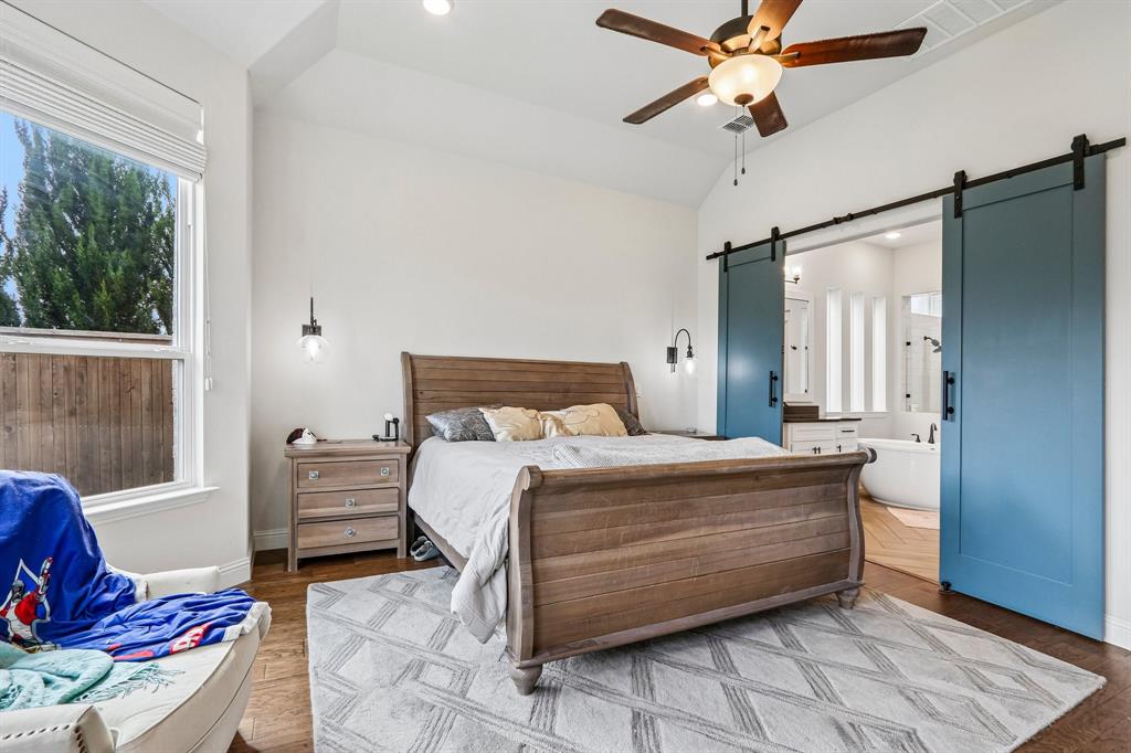 Vaulted ceiling with a ceiling fan, wood-finish flooring, recessed lighting, and wall-mounted sconces