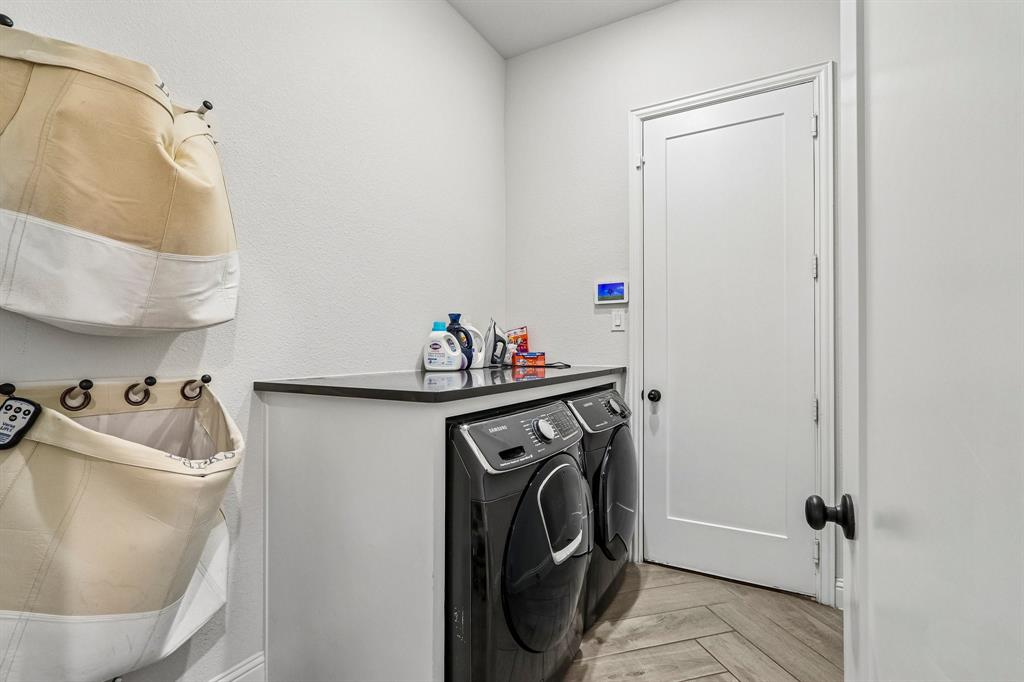 Laundry area featuring a built-in counter, dark flat-panel cabinetry, and herringbone-patterned wood-finish flooring