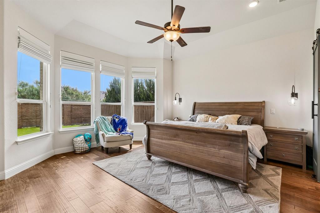Bay window with multiple large windows, wood-finish flooring, recessed lighting, ceiling fan, and wall-mounted sconces
