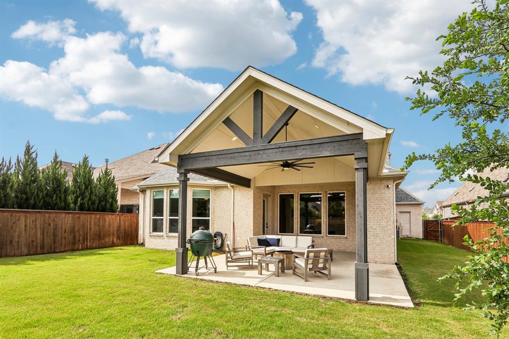 Expansive backyard with a covered patio, vaulted ceiling, and ceiling fan