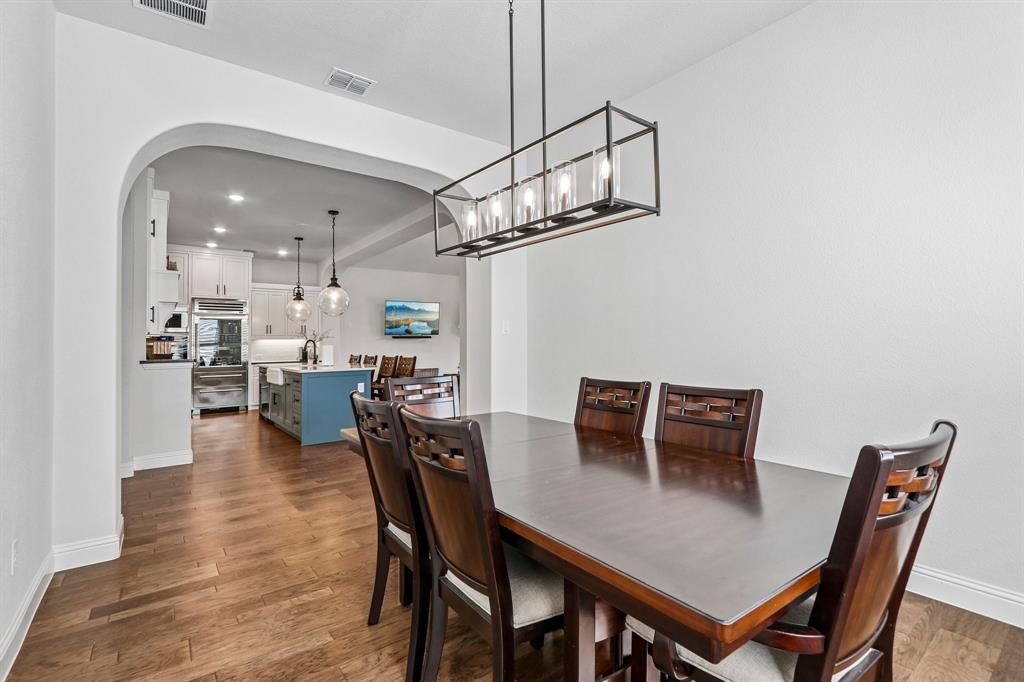 Arched entryway leading to a kitchen with stainless steel appliances, a center island with a built-in sink, and pendant lighting Arched entryway leading to a kitchen with stainless steel appliances, a center island with a built-in sink, and pendant lighting