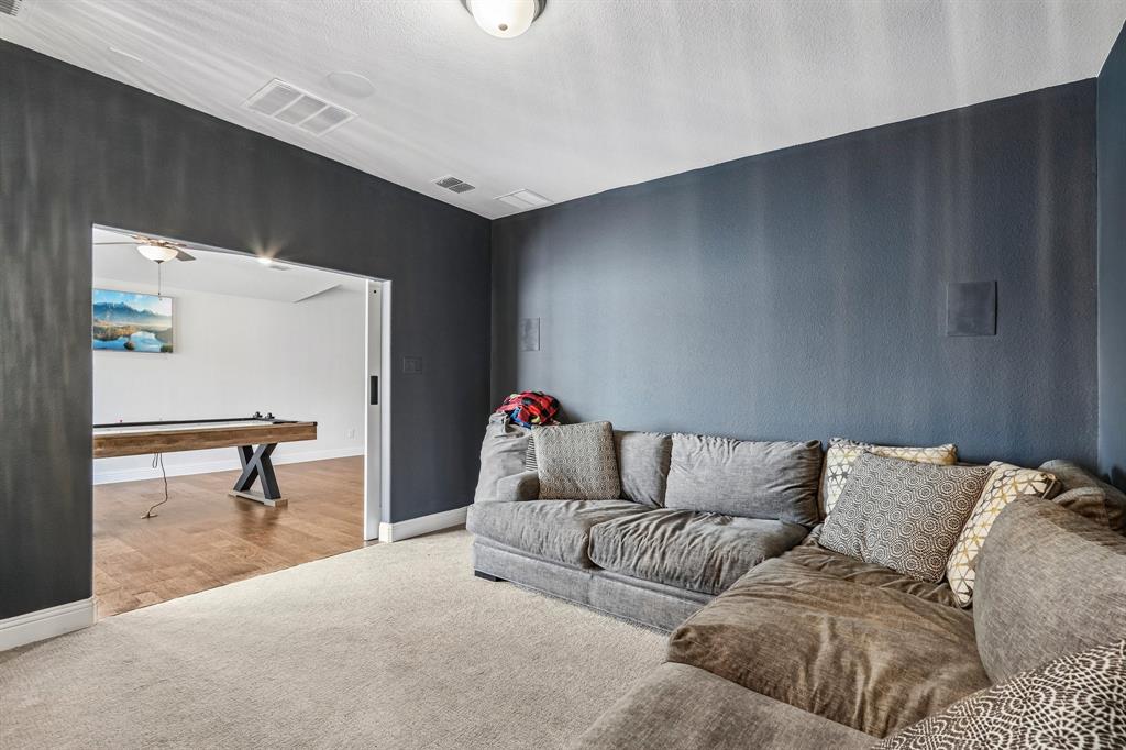 Recessed speaker system, overhead flush mount light fixture, carpeting, wood-finish flooring in adjacent room, and wide entryway